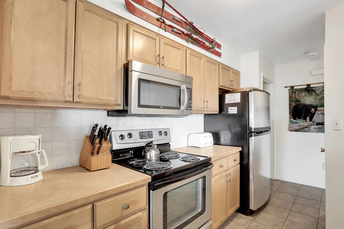 A practical yet stylish kitchen area with wooden cabinetry, modern appliances, and playful ski-themed decor, designed for cooking, family gatherings, and entertaining.