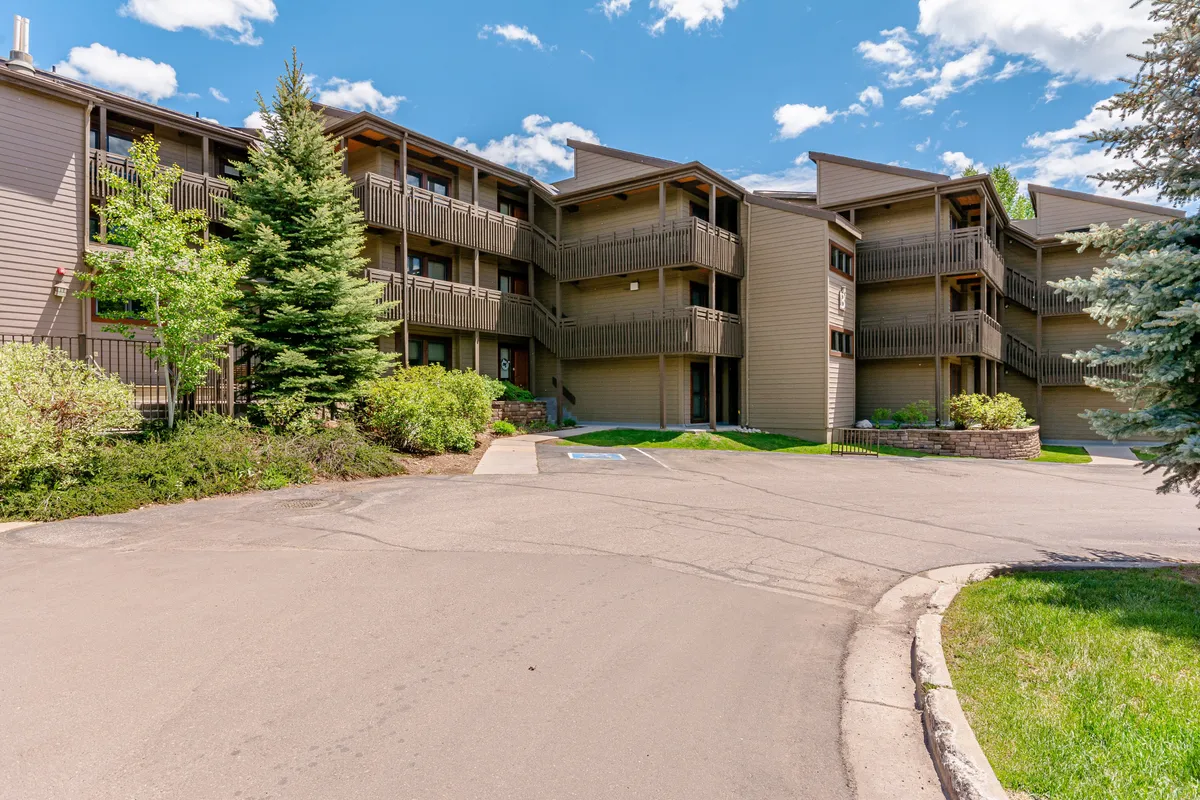 This exterior shot highlights the building's facade with charming balconies and lush landscaping, inviting guests to step outside and explore the walkable surroundings. It evokes the ease of access to nearby restaurants, breweries, and the base area, as referenced in the section.